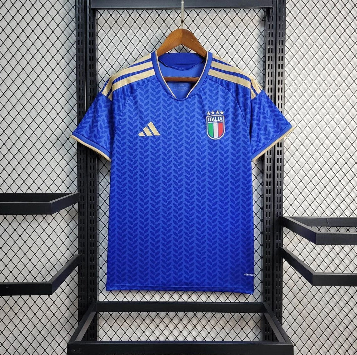 Blue Italy Home jersey with Italian flag emblem on a hanger against a grid background