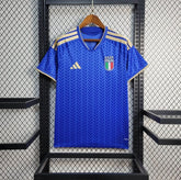 Blue Italy Home jersey with Italian flag emblem on a hanger against a grid background